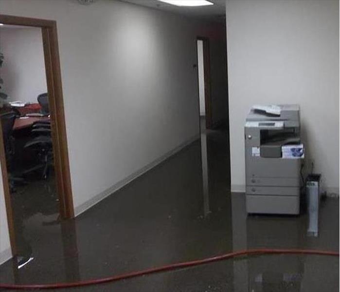 view of office hall area, copy machine and flooded floor with a hose