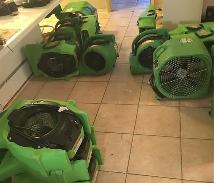 about eight green air movers and axial fans on a tile floor