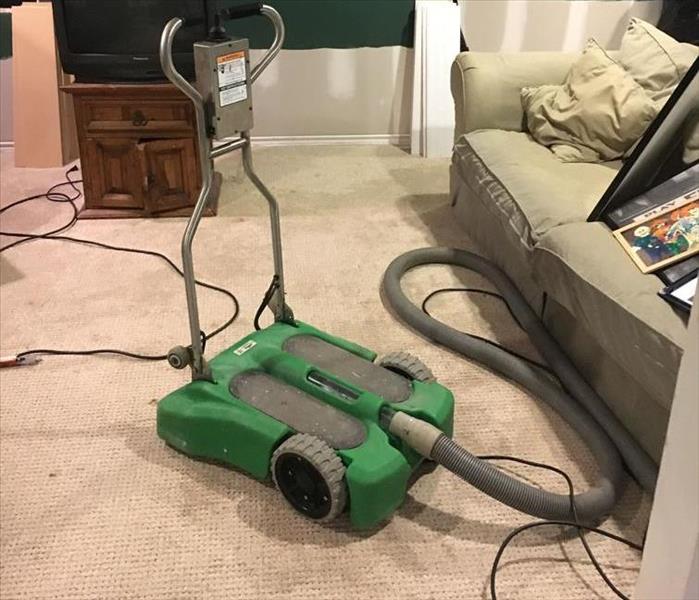 green device with gray hose on a wet carpet